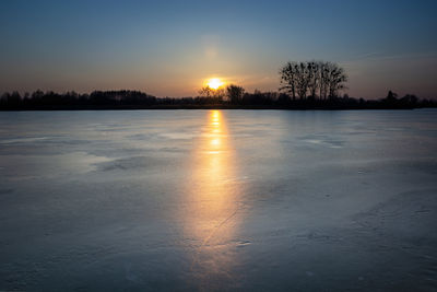 Frozen lake and sunset, horizon and light on the ice pane, eastern poland