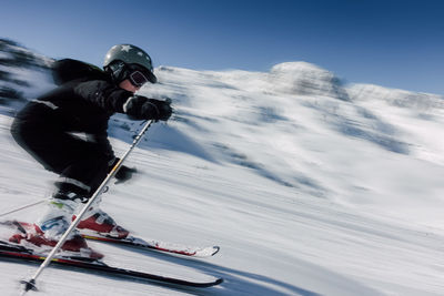 Man skiing on snow covered mountain against sky