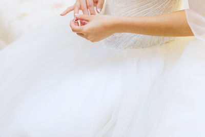 Midsection of woman standing against white wall