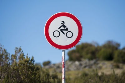 Close-up of road sign against clear blue sky