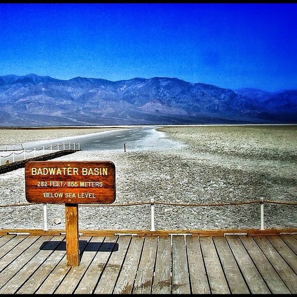 text, western script, mountain, communication, tranquil scene, clear sky, mountain range, sign, tranquility, blue, transportation, capital letter, landscape, information sign, warning sign, scenics, sky, road sign, guidance, railroad track