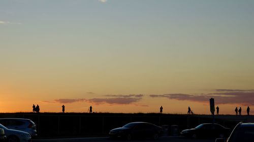 Cars on street against sky during sunset