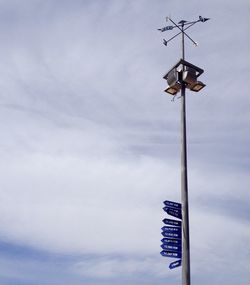 Low angle view of weather vane against cloudy sky