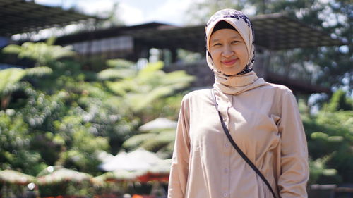 Portrait of woman in hijab standing against plants