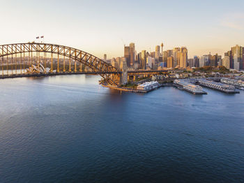 Bridge over river by buildings in city against sky