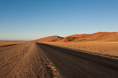 Road amidst desert against clear sky