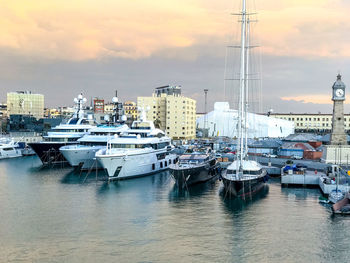 Boats moored in harbor at sunset