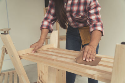 Midsection of woman holding wood at home