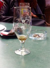 Low section of man drinking glass on table