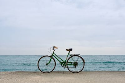 Bicycle on beach against sky