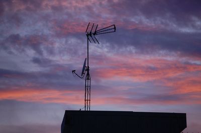 Low angle view of silhouette communications tower against sky during sunset