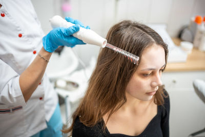 Midsection of beautician giving hair treatment to patient