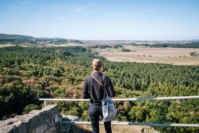 Rear view of woman standing by railing looking at landscape