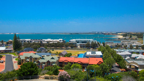 High angle view of buildings and sea against blue sky