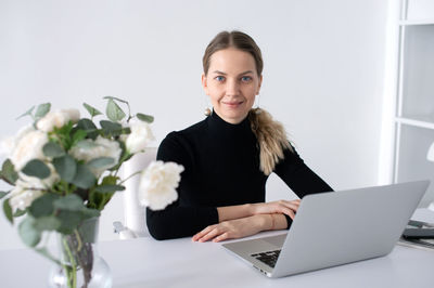 Portrait of young businesswoman using laptop at desk in office