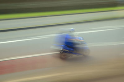 Blurred motion of man riding bicycle on road