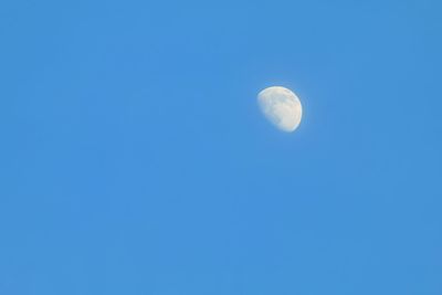 Low angle view of moon against clear blue sky