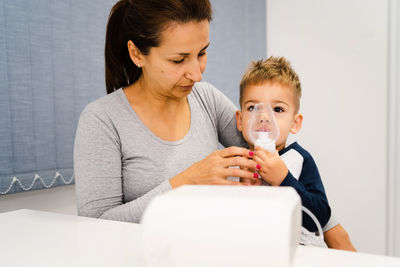 Portrait of mother and son with nebulizer on table