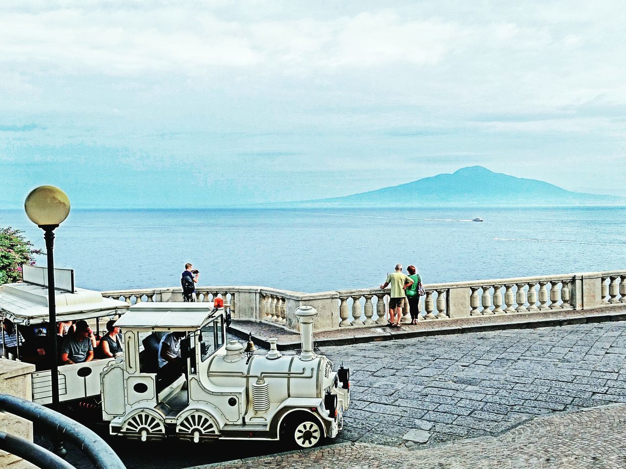 sea, sky, bicycle, railing, water, transportation, mode of transport, men, horizon over water, lifestyles, leisure activity, cloud - sky, nature, mountain, tranquility, land vehicle, scenics, beauty in nature, sitting