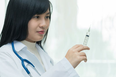 Close-up of doctor looking at injection in hospital