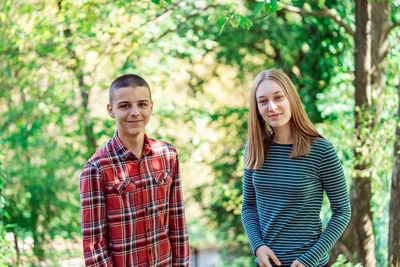 Portrait of smiling young woman standing against trees