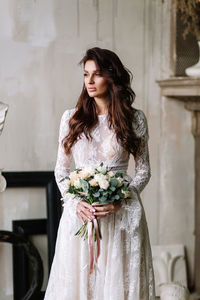 Young woman standing against white wall