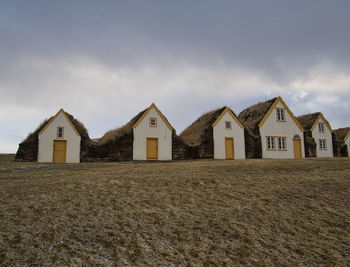 Houses on beach by buildings against sky