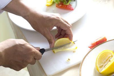 Cropped hands cutting lemon