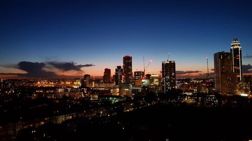 Illuminated cityscape against blue sky at night