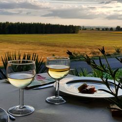 Wine glasses on table against sky