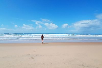 Full length of woman walking at beach against sky