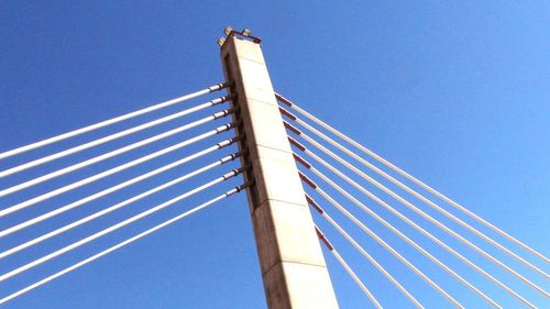 Low angle view of suspension bridge against clear blue sky