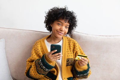 Portrait of young woman sitting on sofa at home