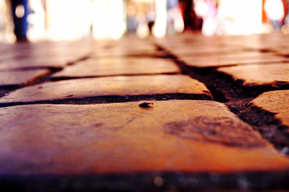 selective focus, surface level, street, focus on foreground, walking, the way forward, sunlight, incidental people, shadow, outdoors, close-up, textured, day, road, footpath, unrecognizable person, low section, sidewalk, men