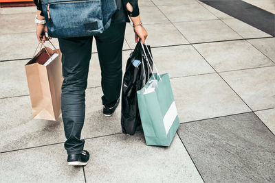 Low section of woman with shopping bags walking on footpath