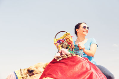 Portrait of smiling young woman holding horse against clear sky