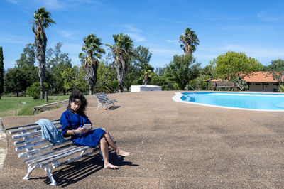 Rear view of woman sitting on lounge chairs at park