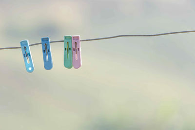Low angle view of clothespins hanging on rope against the sky