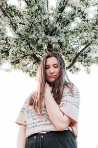 Portrait of beautiful young woman against plants against trees