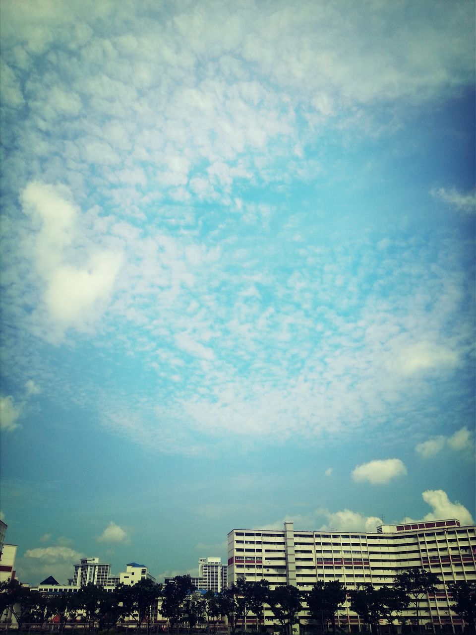 architecture, building exterior, sky, built structure, cloud - sky, low angle view, cloudy, city, cloud, building, blue, residential building, outdoors, day, cityscape, no people, overcast, residential structure, city life, weather