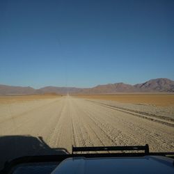 Road leading towards mountains against blue sky