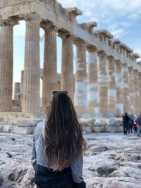 Woman with arms outstretched standing in front of historical building