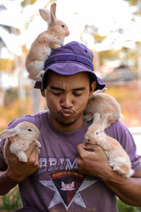 Young man puckering while holding rabbits