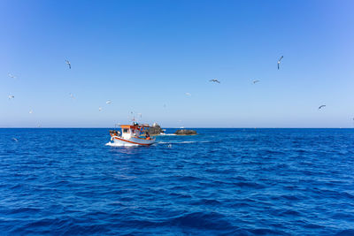 Boat in sea against clear blue sky