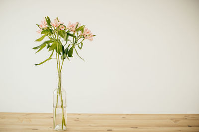 Flower vase on table against wall