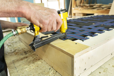 Stapling elastic band with a yellow pneumatic stapler. furniture manufacture shot.