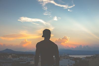 Rear view of man standing against sky during sunset