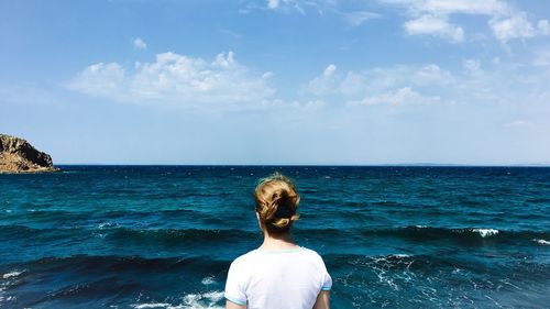 Rear view of woman standing by sea against sky