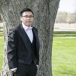 Portrait of well-dressed young man standing against tree trunk
