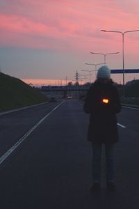 Rear view of silhouette man standing on road at dusk